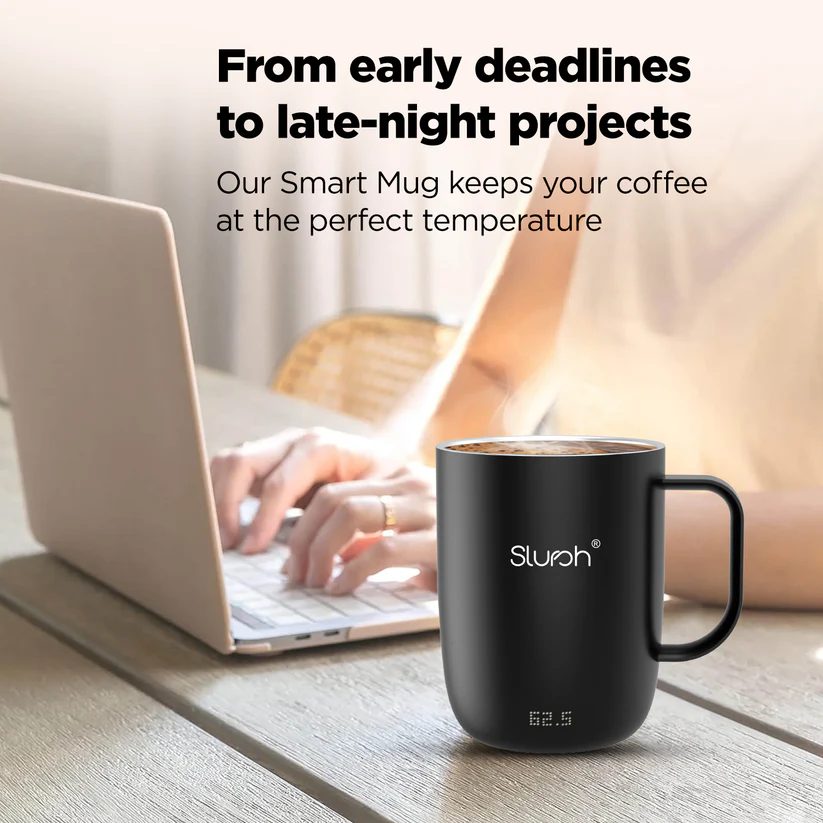 A laptop user with a Slursh smart mug nearby on a wooden desk